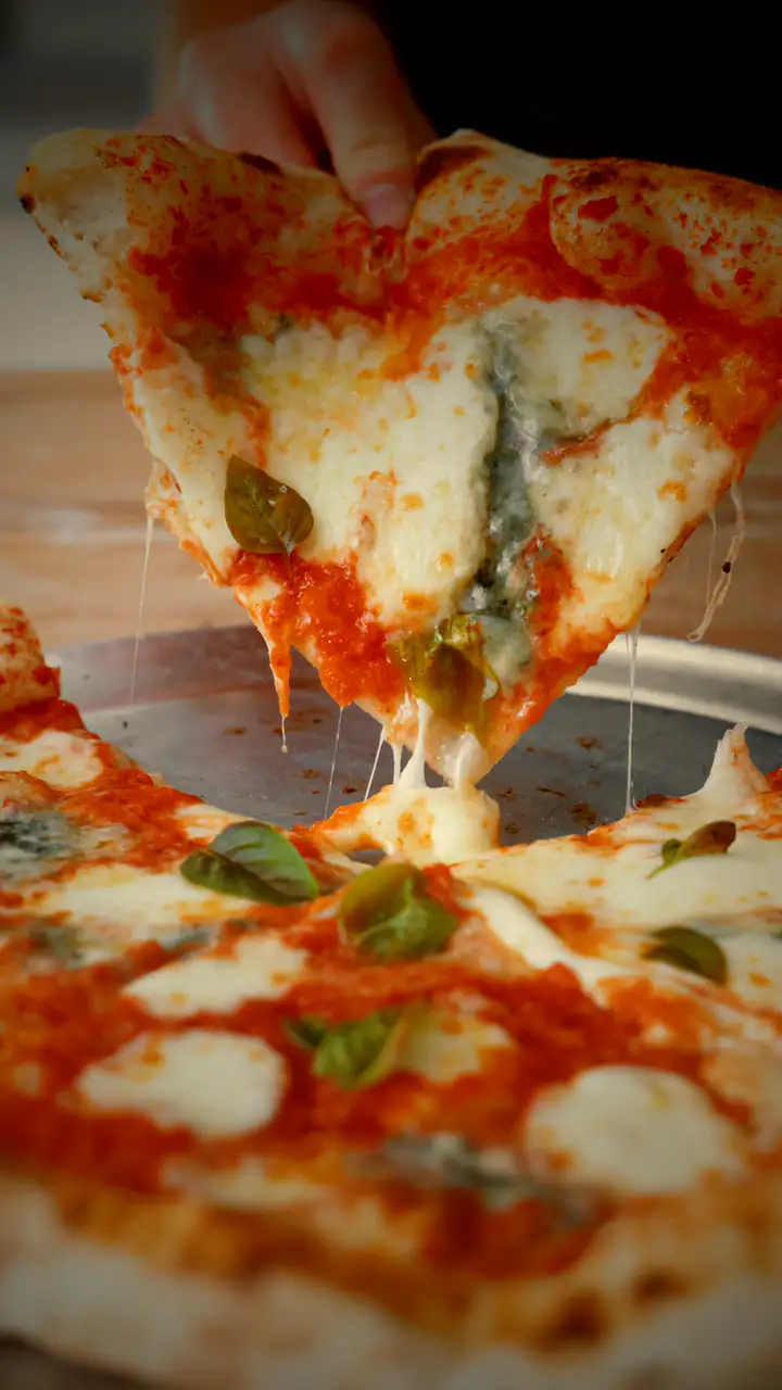 O felie de pizza margherita ridicată din pizza, cu fire de mozzarella