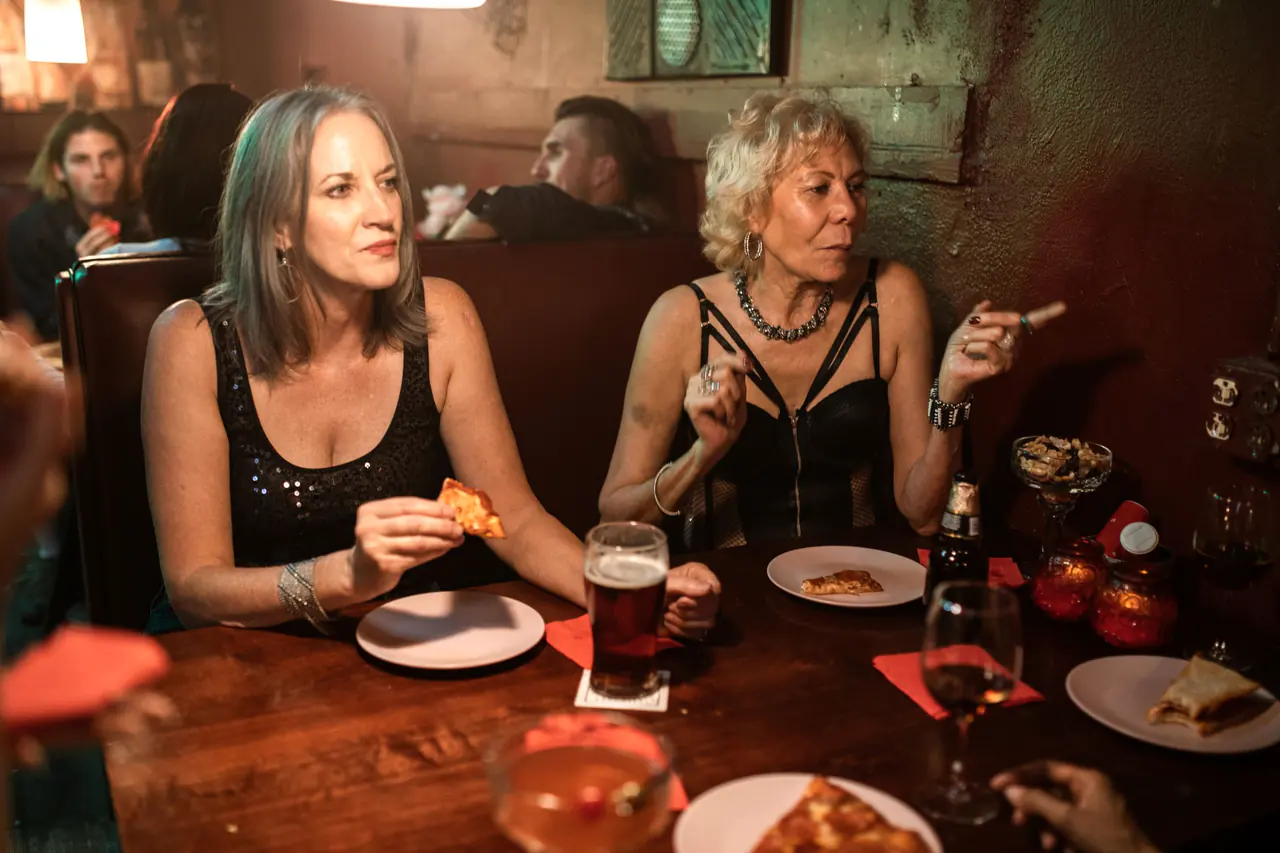 Două prietene la masă într-un restaurant cald, seara, cu pizza și bere